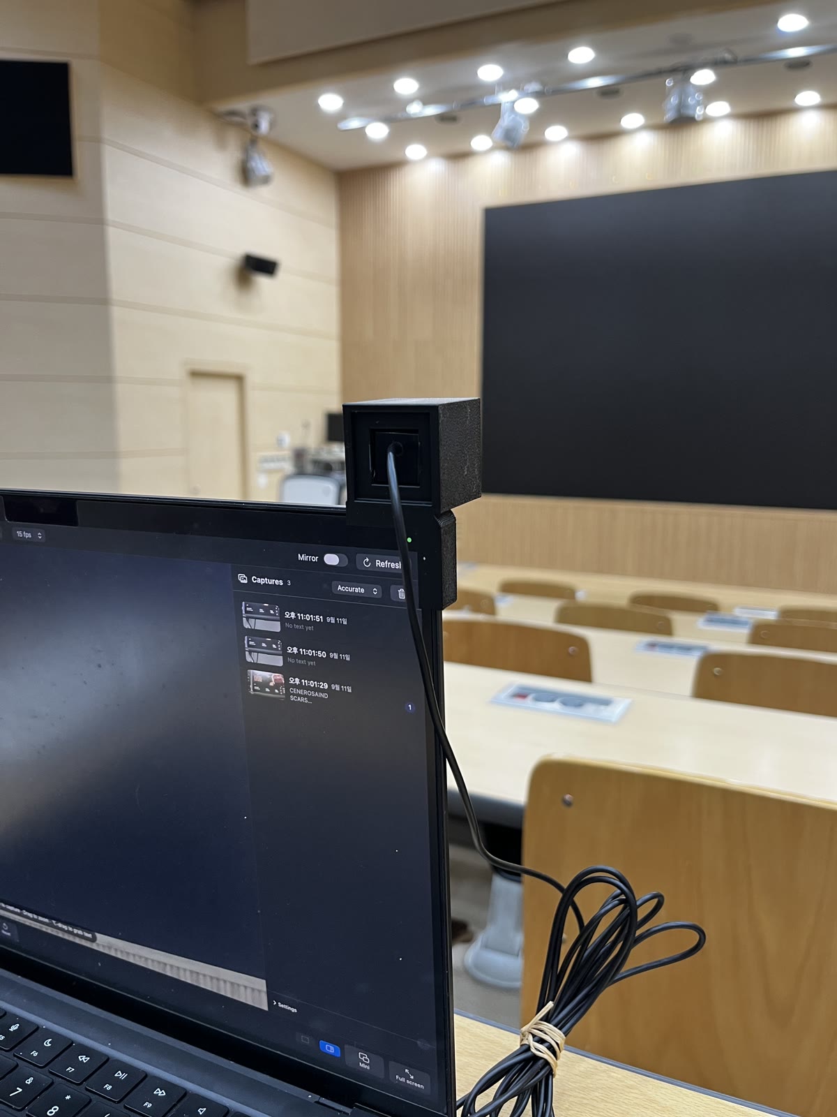Portrait photo from behind the seat: the cube on the MacBook's top right corner, the Cyclops app open on screen, the cable coiled on the desk